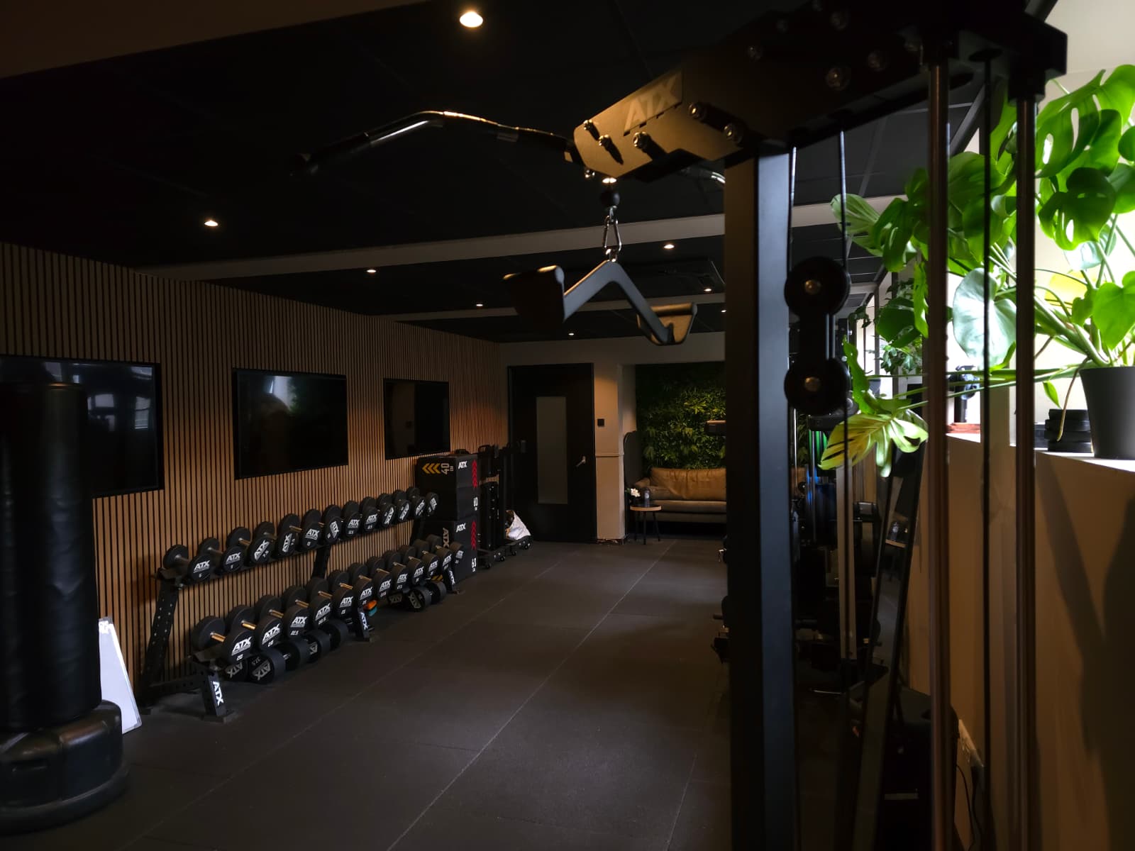 Interieur van de sportschool van Het Krachtkantoor in Veenendaal, met een functional trainer, dumbbells en een sfeervolle loungehoek